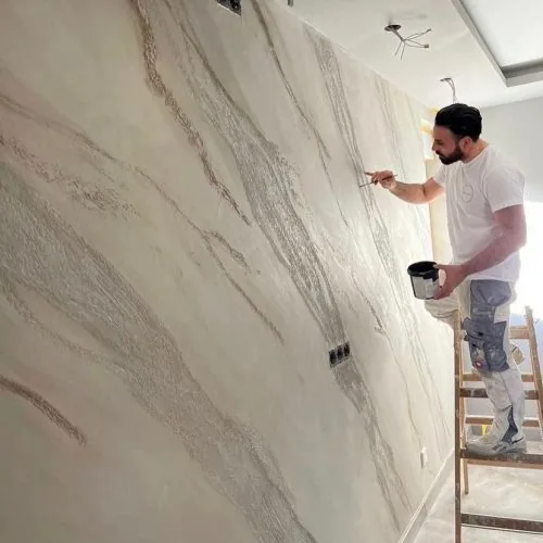 Handwerker zeichnet mit dem Pinsel Adern in eine großflächige Marmoroptik