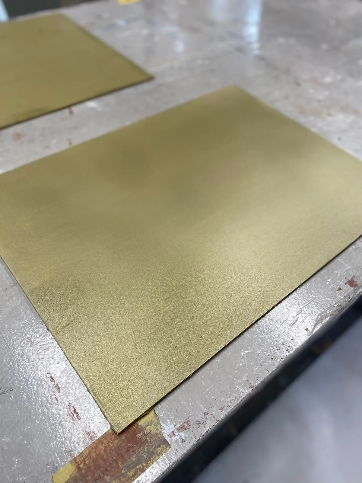 Gespachtelte Metalloberfläche in warmem Goldton mit sichtbarer Struktur