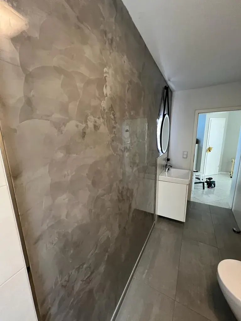 Badezimmer mit Wänden in ruhiger Betonoptik, fugenlos über die Ecken geführt