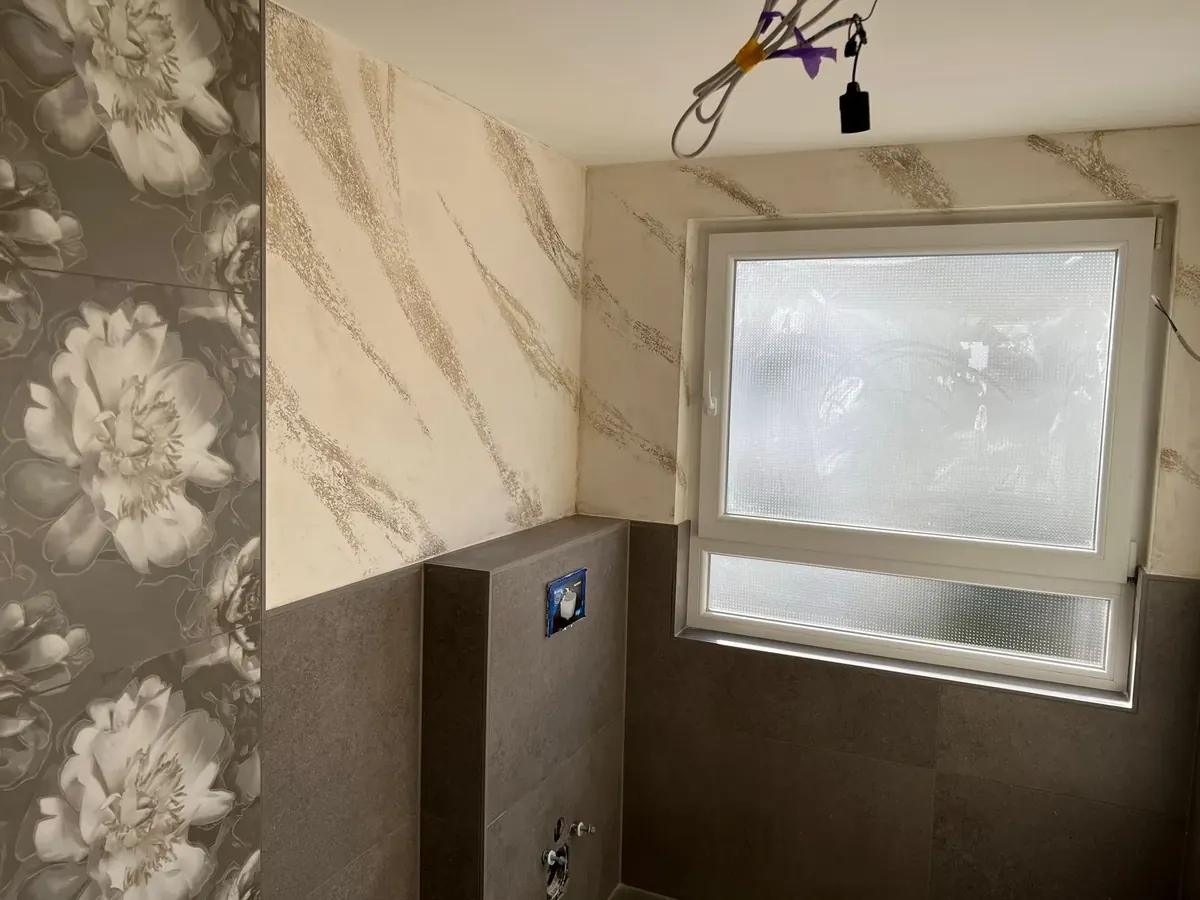 Badezimmer mit einer floral gemusterten Wand neben einer Fläche in Marmoroptik