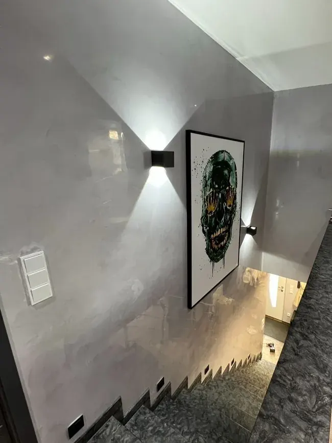 Flur mit zweifarbig abgesetzter Spachtelwand, Wandleuchte und gerahmtem Bild