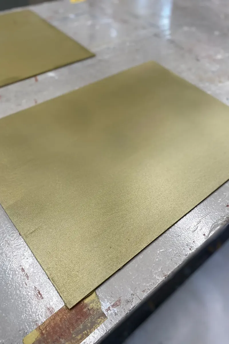 Musterplatte mit Blattgold-Optik auf gespachteltem Untergrund, im Werkstattlicht