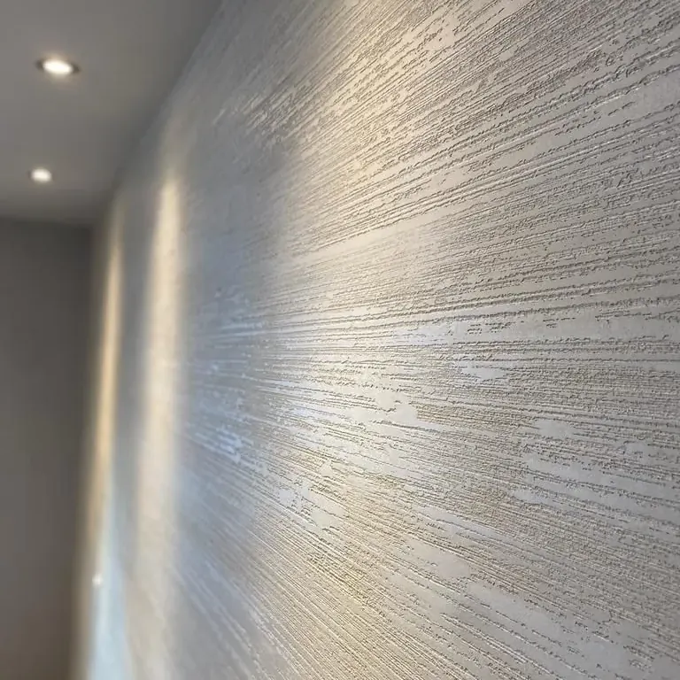 Silbrig schimmernde Metallspachtelung mit weichem Verlauf an einer Wand