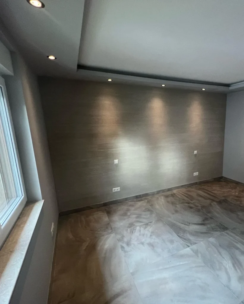 Sanierter Raum mit frisch gespachtelter Wand und eingebauter Deckenbeleuchtung