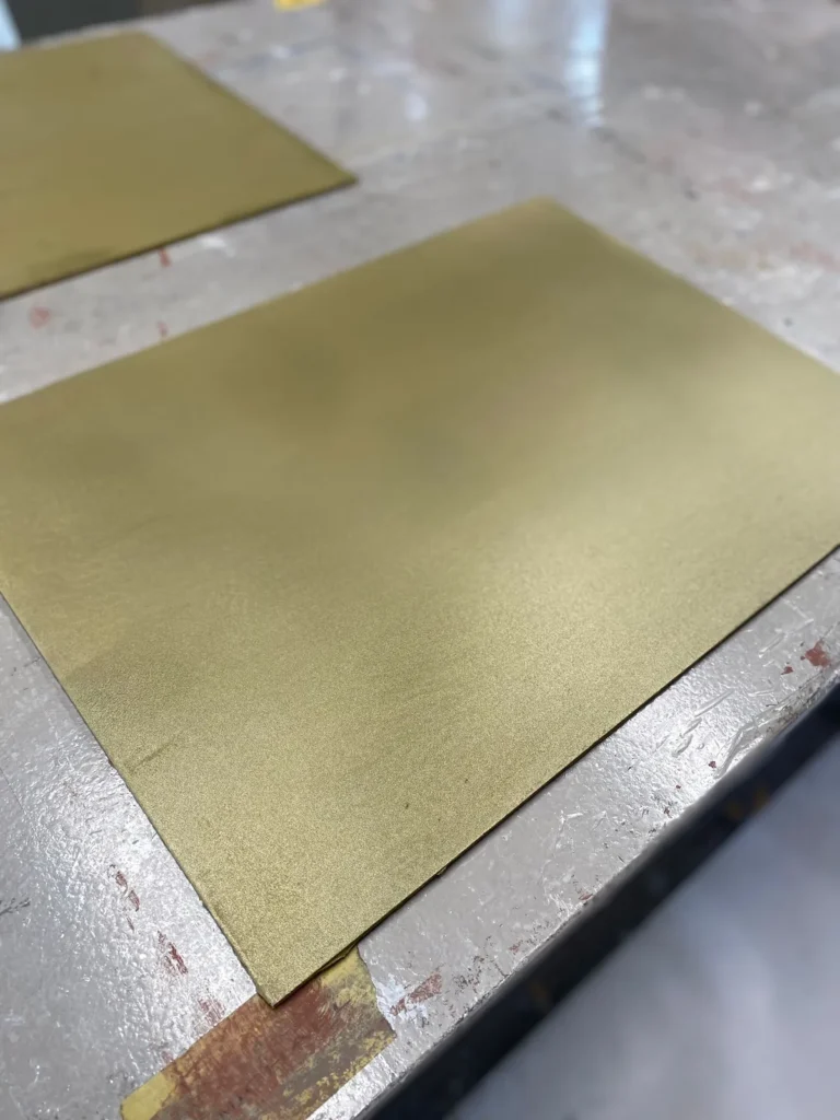 Große Platte mit goldener Metalloberfläche auf einem Werkstattboden